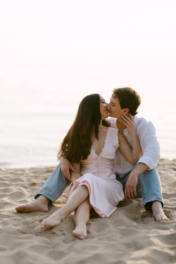 couple kissing sitting in the sand of lake michigan