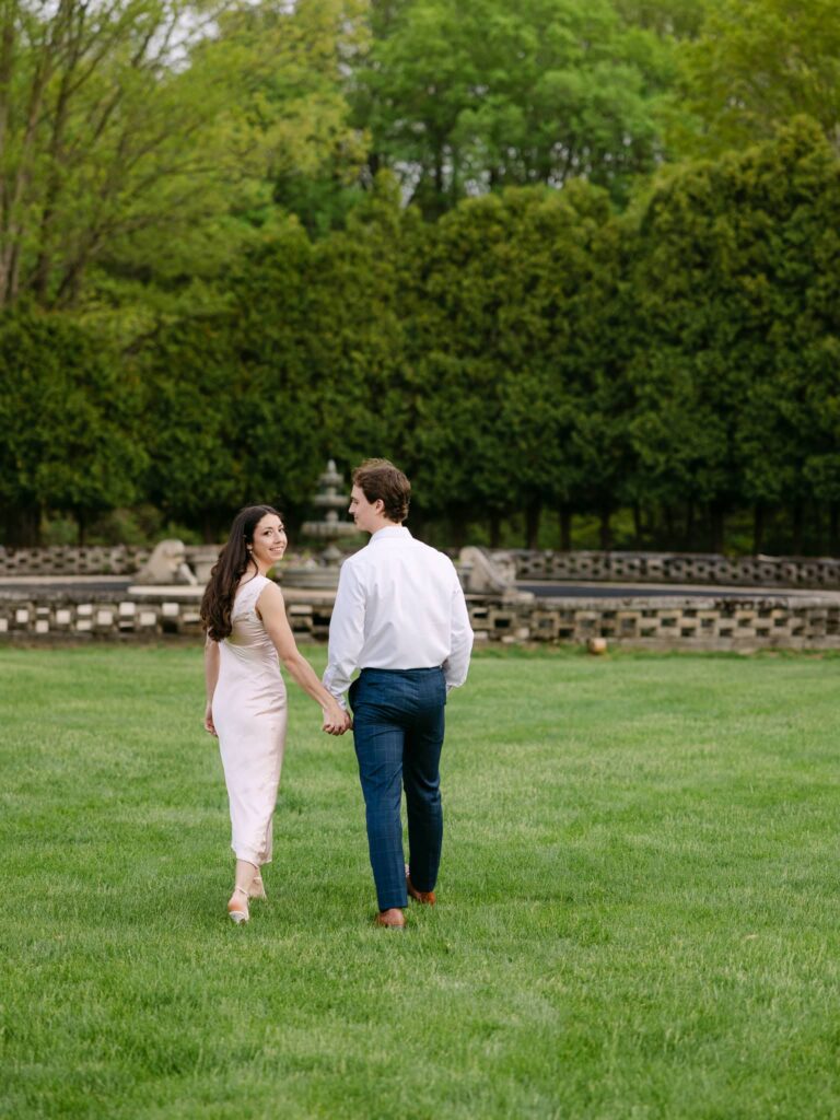 Holding hands walking on the grounds at The felt Mansion with francesca looking back