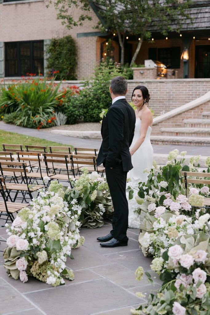 Bride and groom walking through floral lined aisle at basil Place-refined, graceful wedding photography