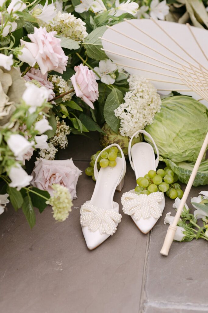 bridal shoe with a pearl bow and florals with grapes and cabbage