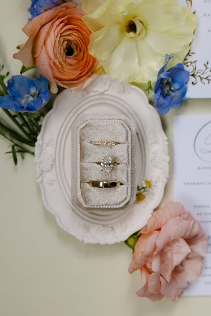 details of the bride and groom rings placed in a ring box surrounded by flowers